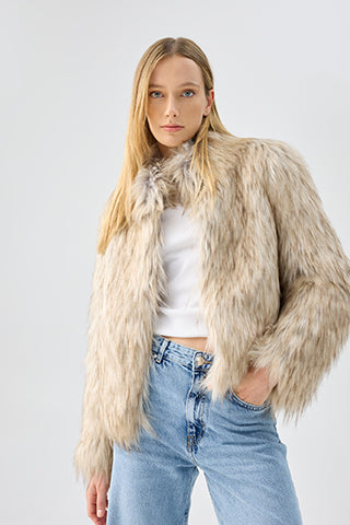 Woman wearing a beige faux fur jacket over a white shirt