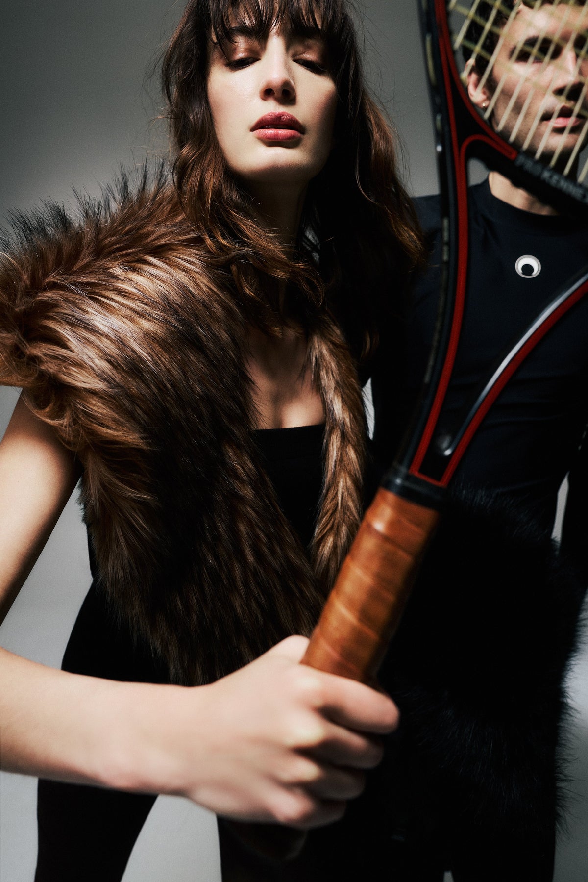 Model wearing a brown faux fur scarf and holding a tennis racket