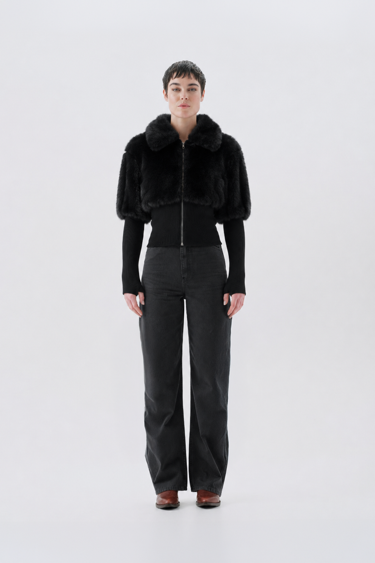 A model wearing a black faux fur jacket with a fluffy collar.