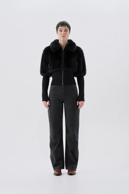 A model wearing a black faux fur jacket with a fluffy collar.