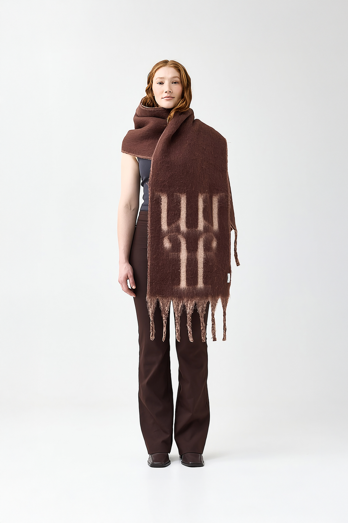 Model wearing a brown scarf with a reversible beige color and the brand logo on a white background