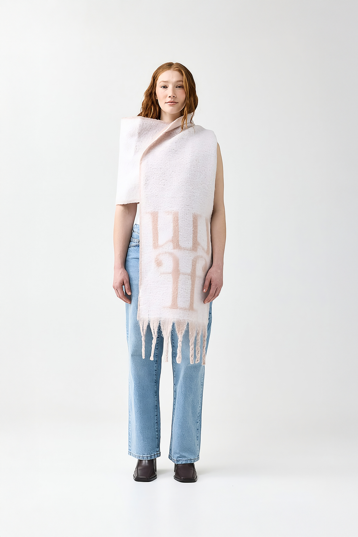 Model wearing a light pink scarf with a reversible white color and the brand logo on a white background