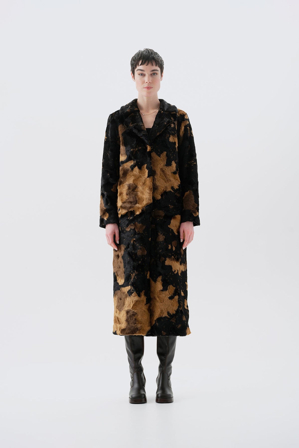 Model wearing a long black and brown faux fur coat with a cow pattern