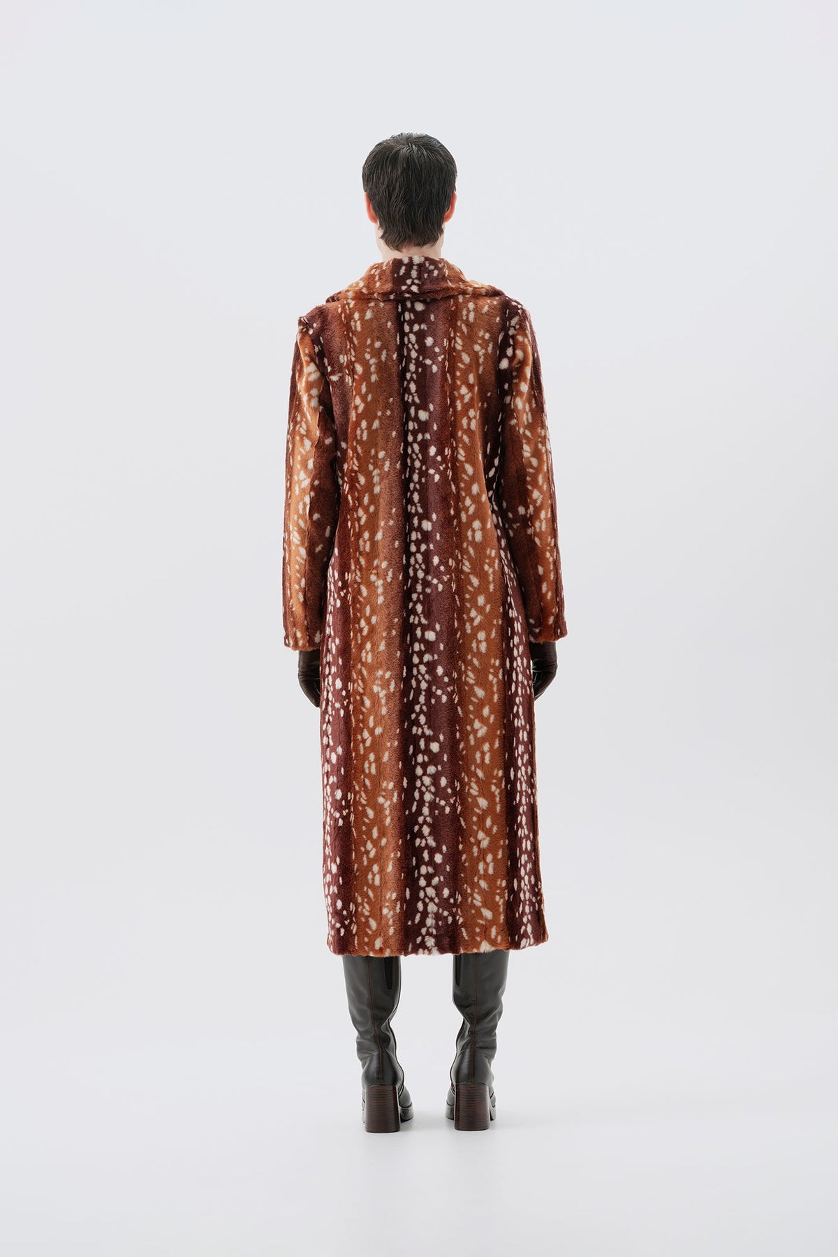 Model pictured from the back wearing a long brown faux fur coat with a bambi pattern on a white background