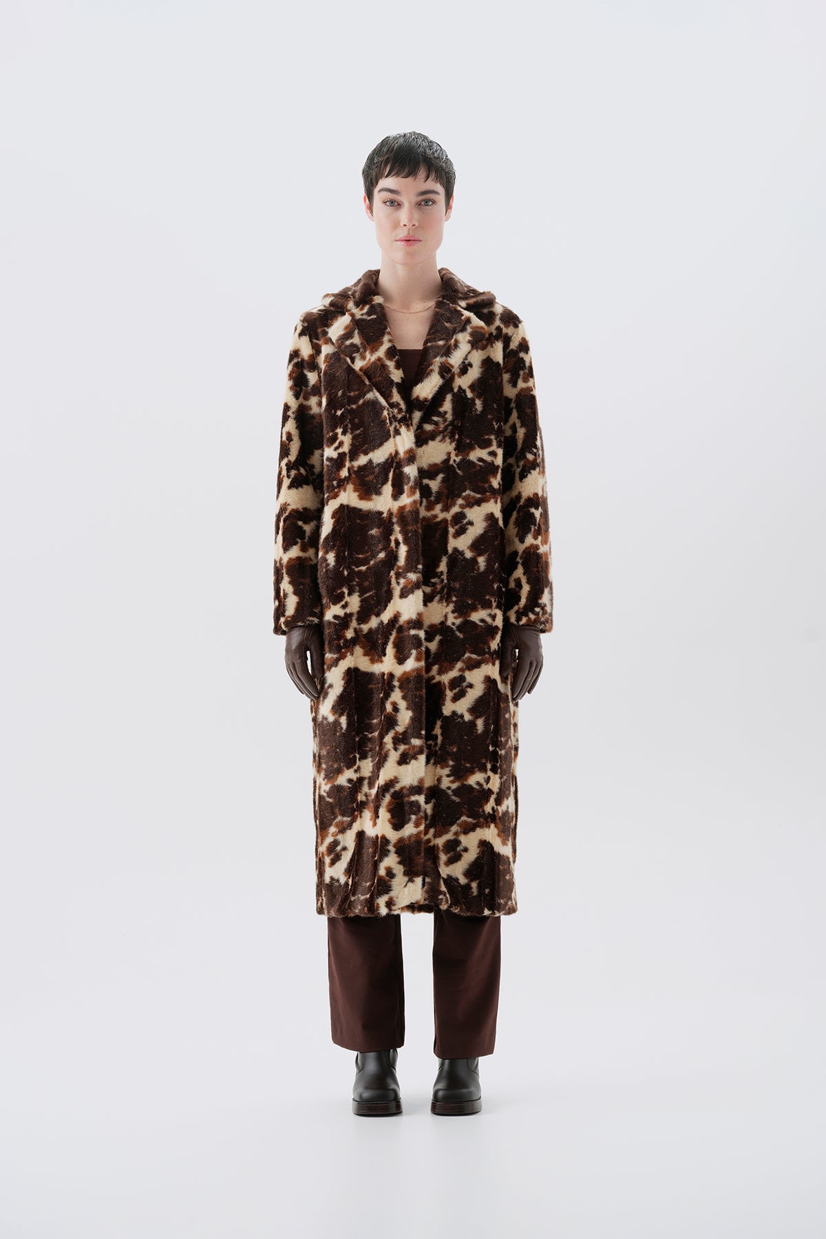 Model wearing a faux fur cow print long coat on a white background