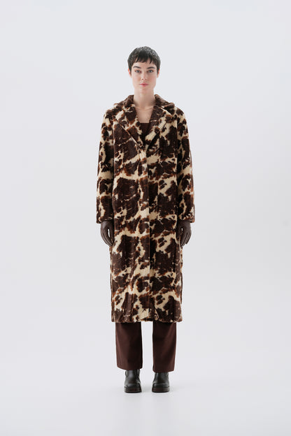 Model wearing a faux fur cow print long coat on a white background