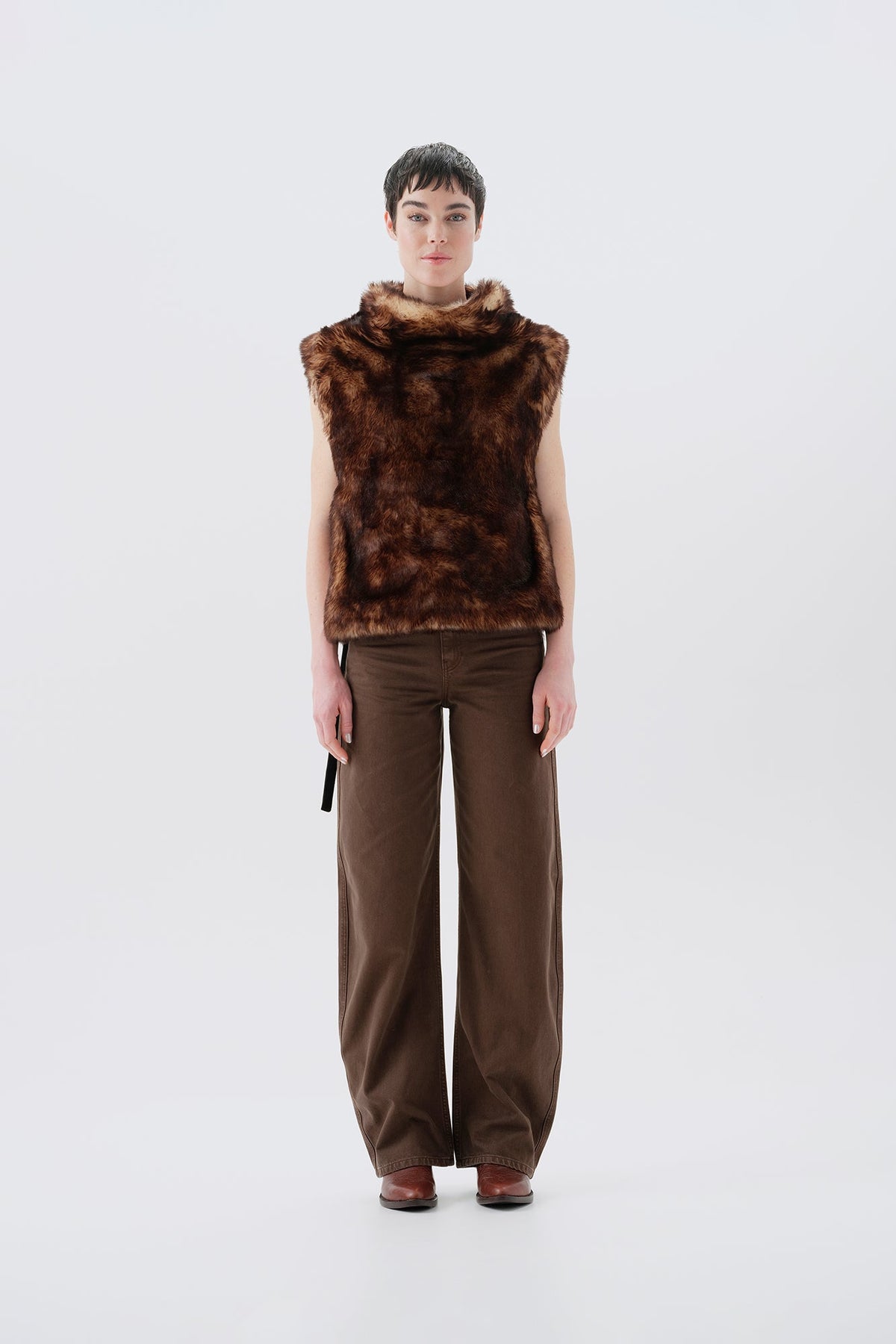 Model wearing a brown faux fur vest and pants on a white background