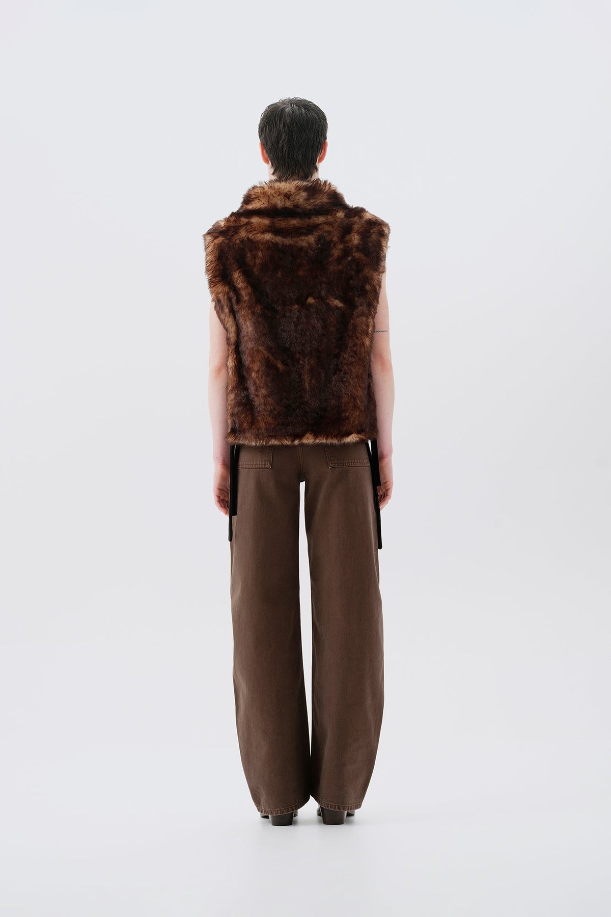 Model pictures from the back wearing a brown faux fur vest and pants on a white background