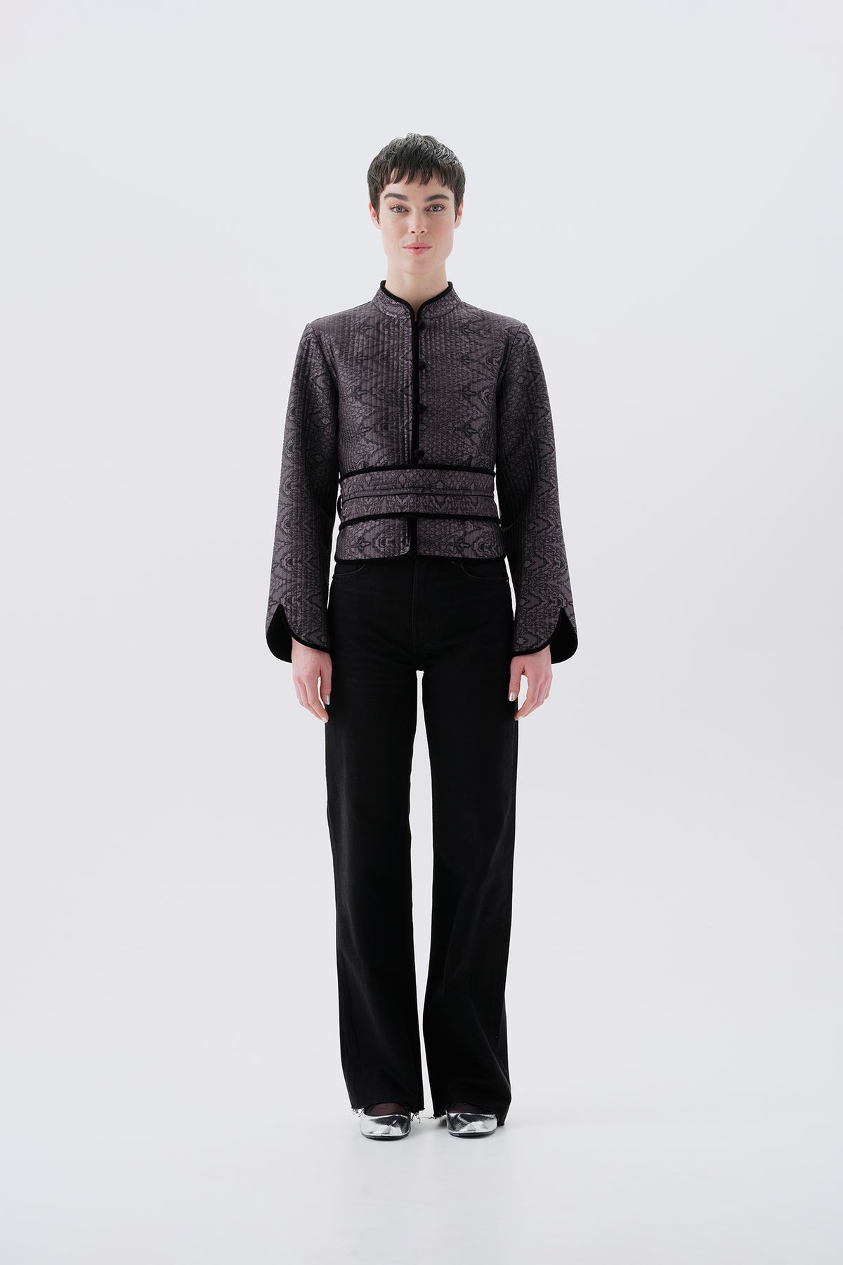 Model wearing a gray jacket with oriental patterns and a black reversible side