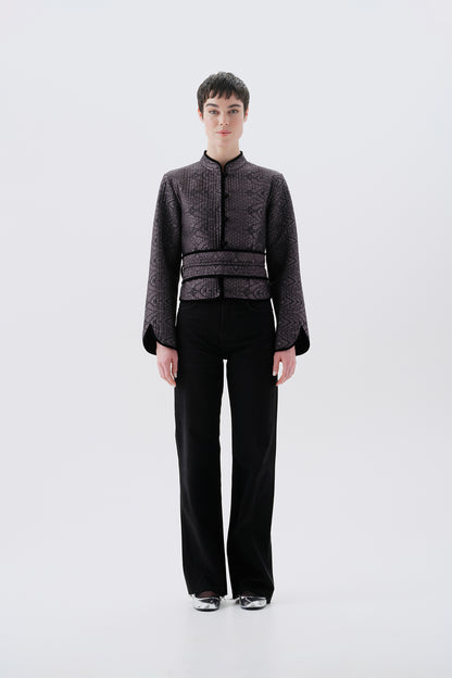 Model wearing a gray jacket with oriental patterns and a black reversible side