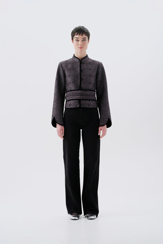 Model wearing a gray jacket with oriental patterns and a black reversible side