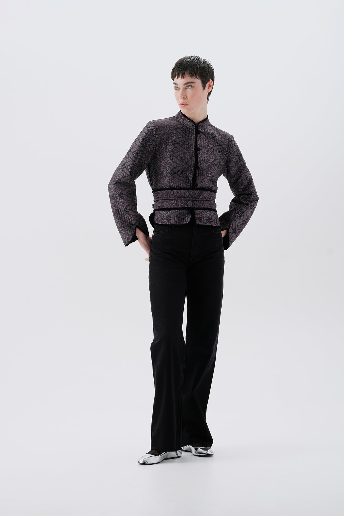 Model wearing a gray jacket with oriental patterns and a black reversible side