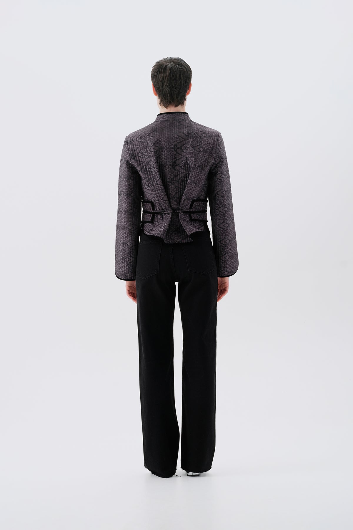 Model wearing a gray jacket with oriental patterns and a black reversible side