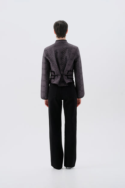 Model wearing a gray jacket with oriental patterns and a black reversible side