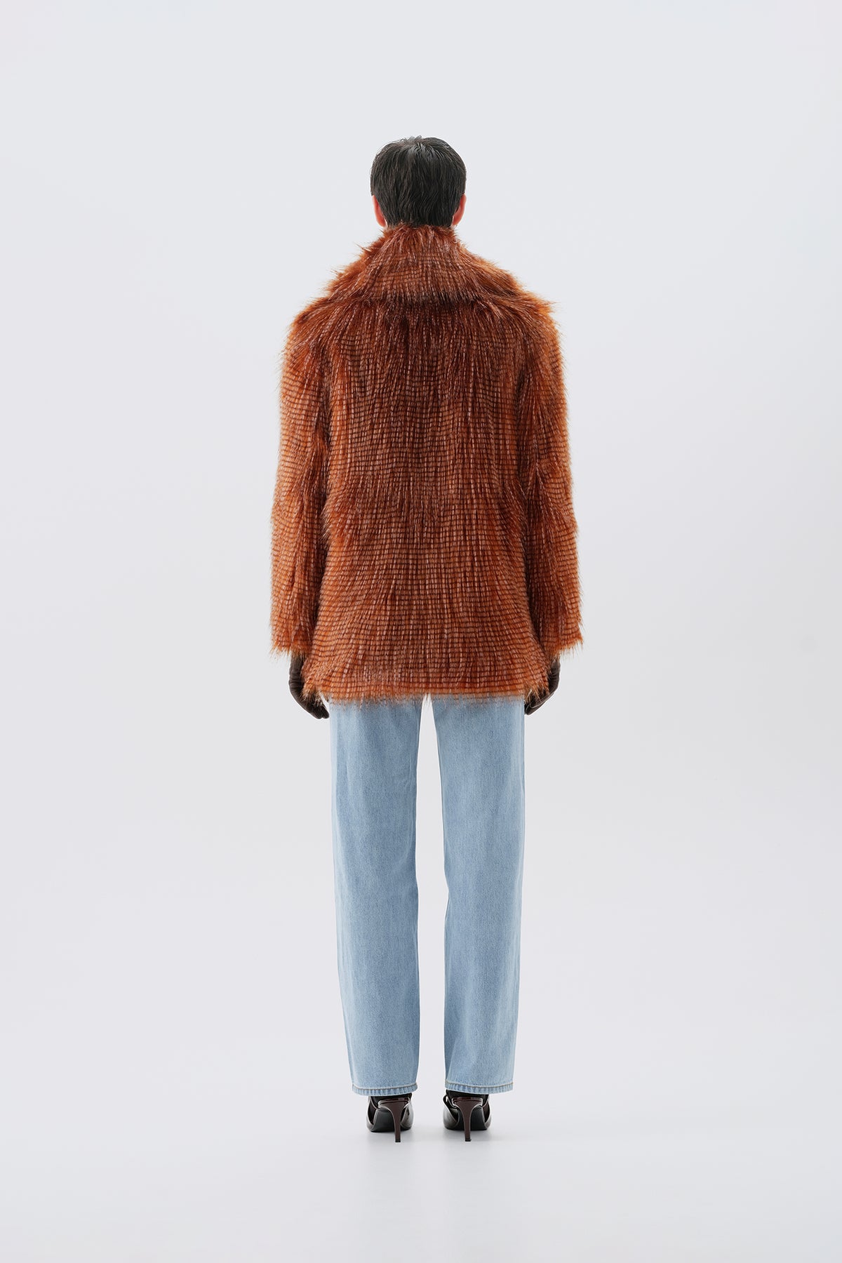 Model pictured from the back  wearing a brown faux fur coat with a white background