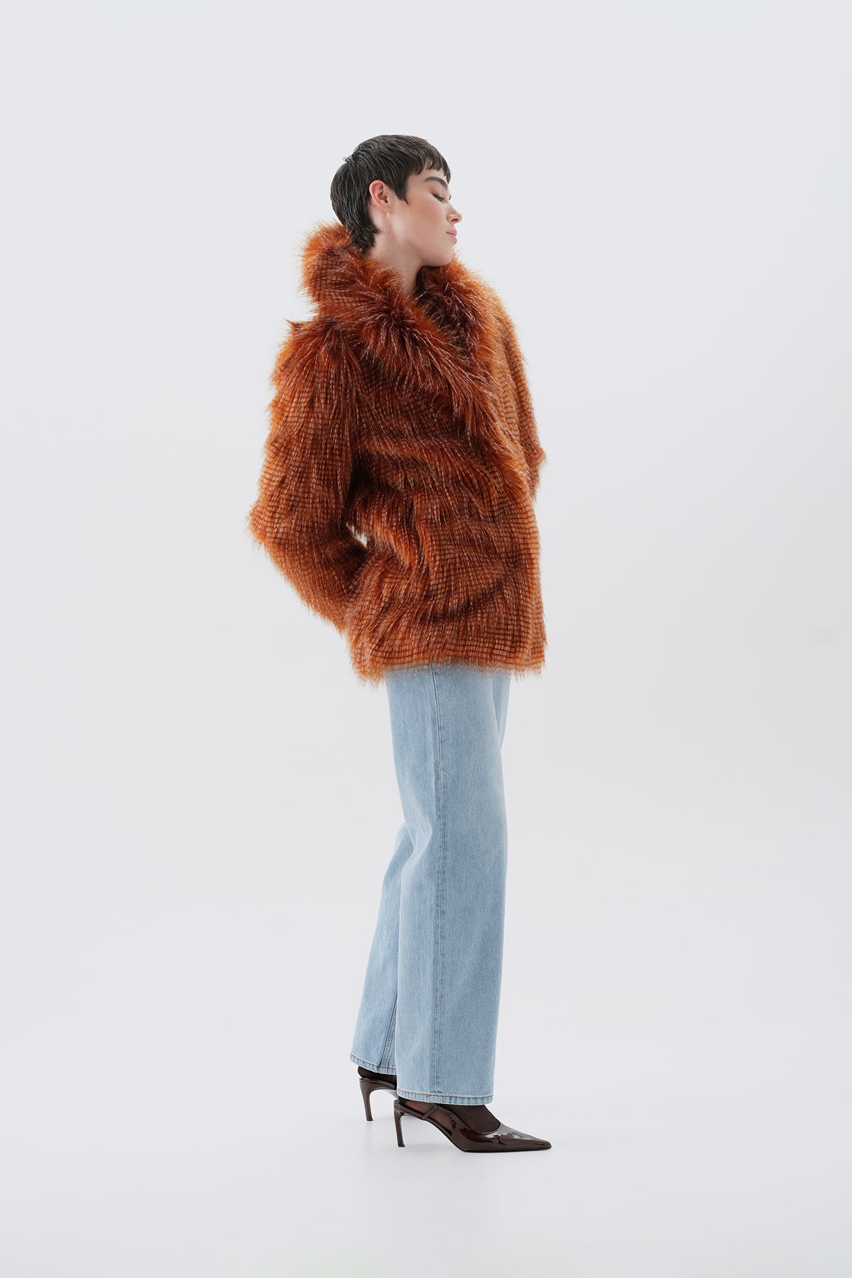 Model wearing a brown faux fur coat and light blue jeans