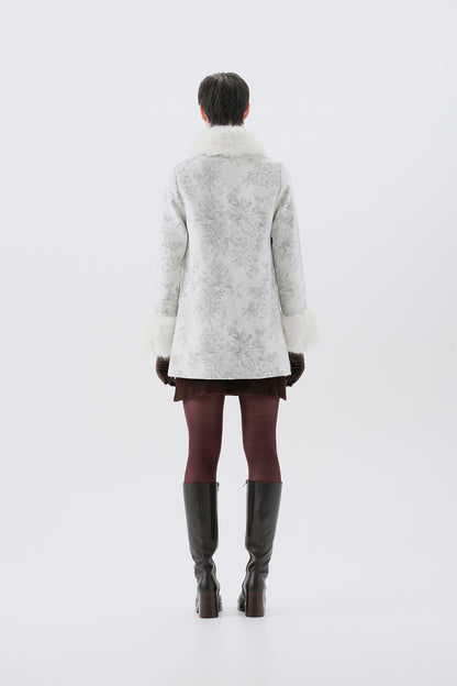A model viewed from the back wearing a patterned white and grey faux-fur coat with white faux-fur collar and cuffs.