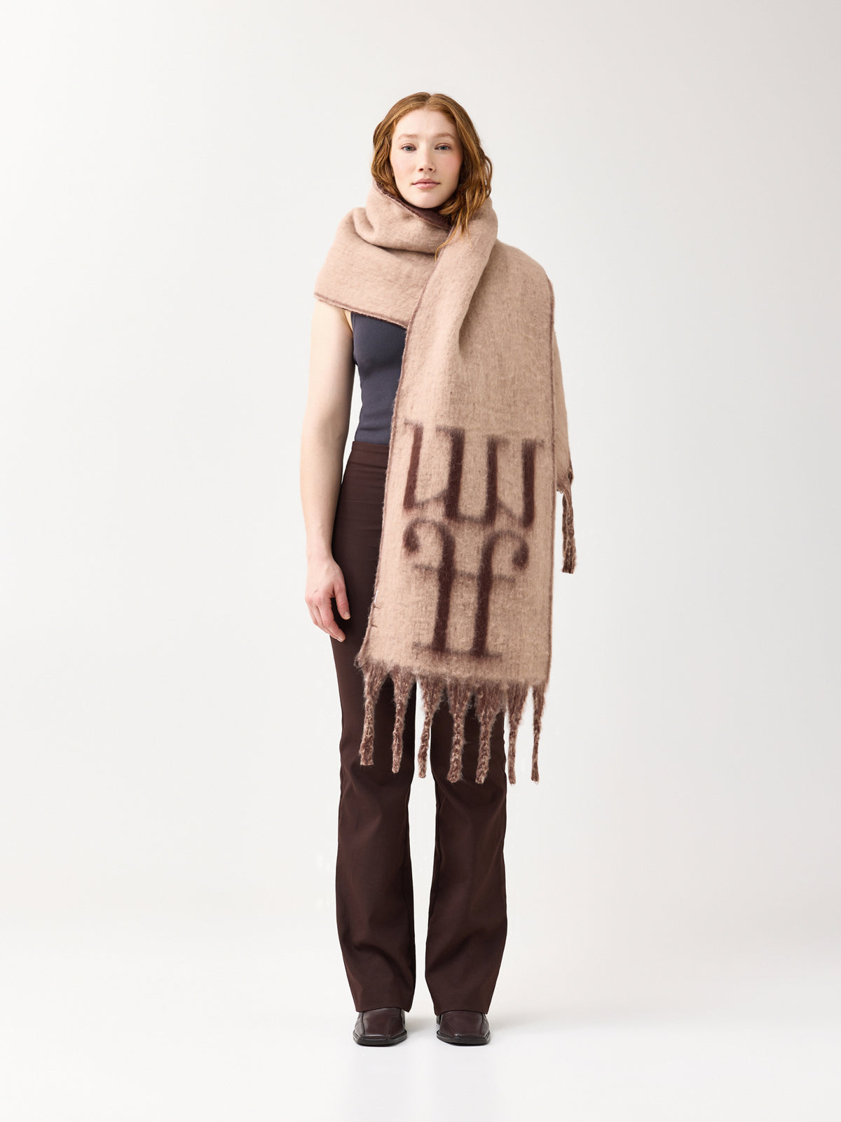 Model wearing a beige scarf with a reversible brown color and the brand logo on a white background