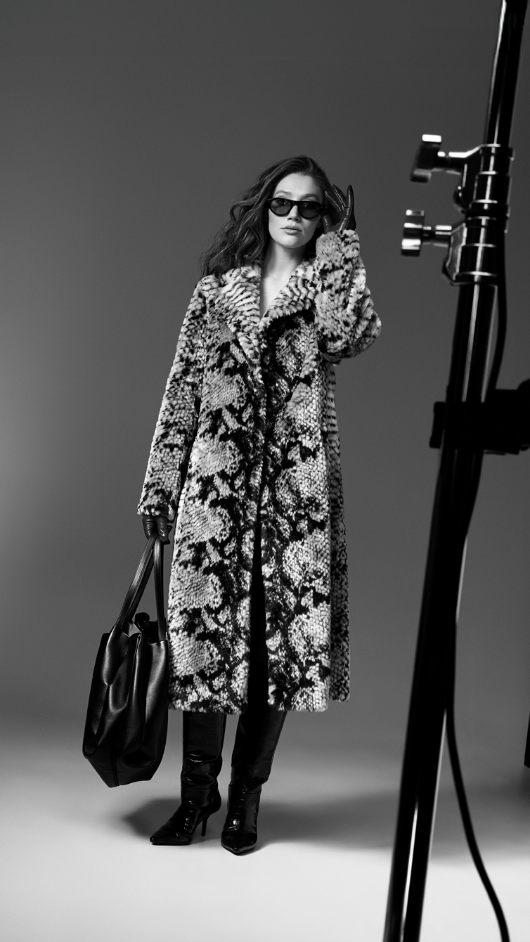 Person in a floral coat standing in a studio with photography equipment.